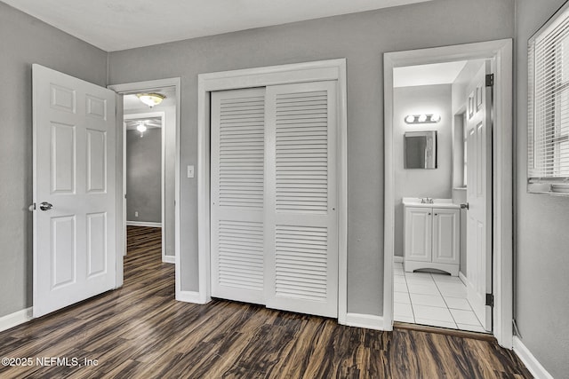 unfurnished bedroom with a closet, baseboards, and dark wood-type flooring