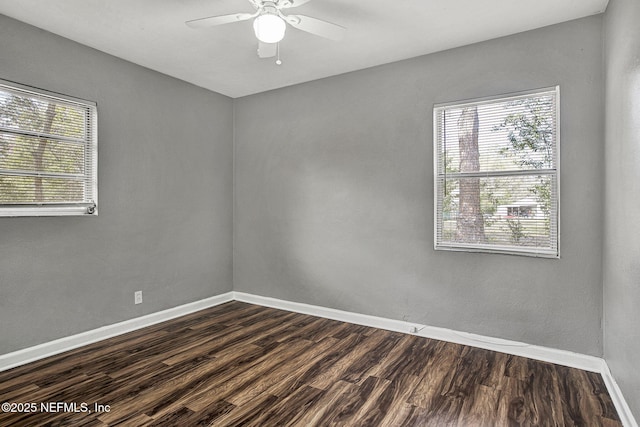 spare room with a healthy amount of sunlight, baseboards, and dark wood finished floors