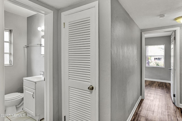 corridor featuring dark wood-style floors, baseboards, and a sink