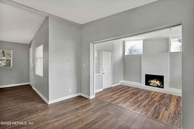 unfurnished living room featuring a fireplace, baseboards, and wood finished floors