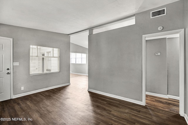 unfurnished room featuring lofted ceiling, visible vents, baseboards, and wood finished floors