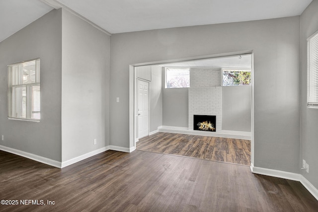 unfurnished living room with a brick fireplace, baseboards, and wood finished floors