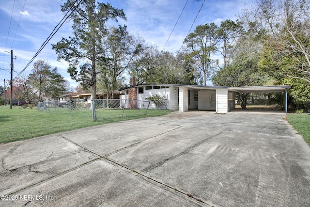 view of front facade with a chimney, concrete driveway, fence, a carport, and a front lawn