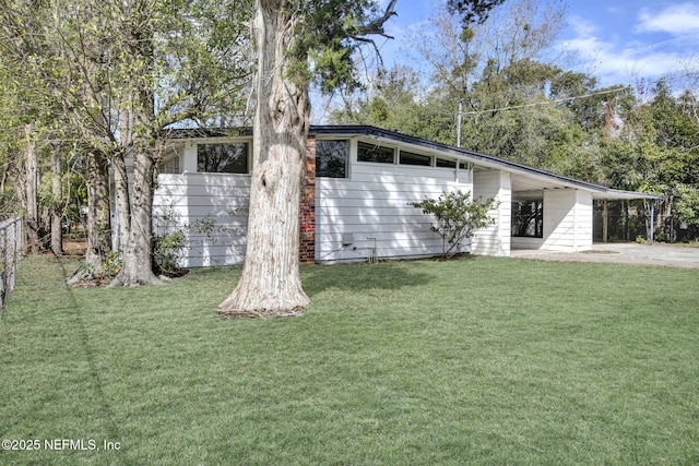 exterior space featuring driveway, fence, an attached carport, and a yard