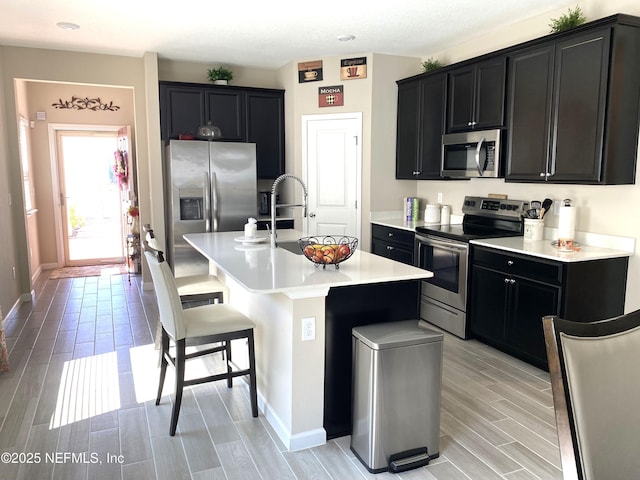 kitchen featuring stainless steel appliances, a kitchen bar, and dark cabinets