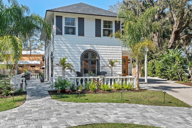 view of front of home with concrete driveway, roof with shingles, and fence