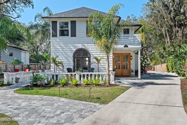 view of front of home with a shingled roof, fence, and french doors