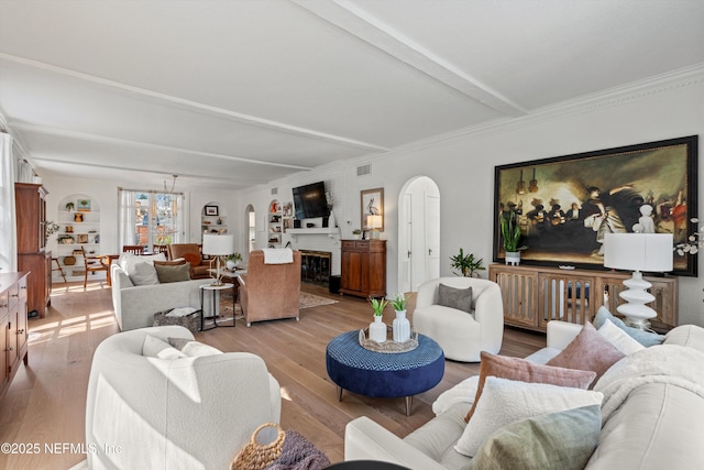 living area with arched walkways, a fireplace, visible vents, light wood-type flooring, and beamed ceiling