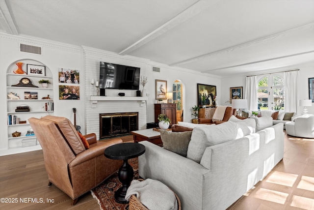 living area with beamed ceiling, a fireplace, wood finished floors, and visible vents