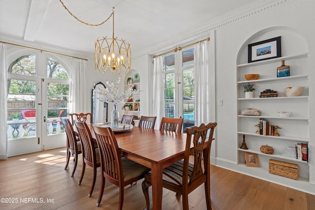 dining room featuring built in shelves, wood finished floors, and french doors