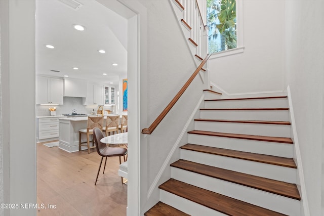 stairs with wood finished floors and recessed lighting