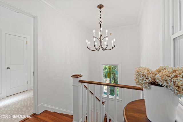 hall with a chandelier, wood finished floors, an upstairs landing, baseboards, and crown molding