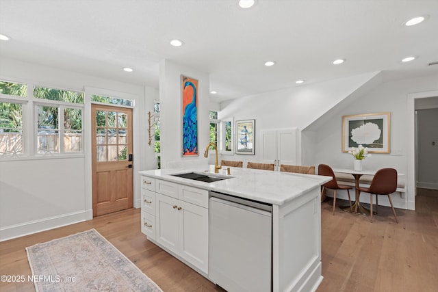 kitchen with light wood finished floors, dishwashing machine, white cabinetry, a sink, and recessed lighting