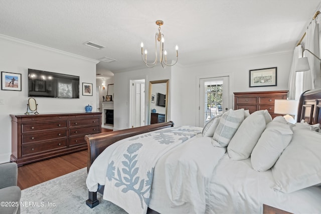 bedroom with a fireplace, visible vents, ornamental molding, wood finished floors, and access to outside