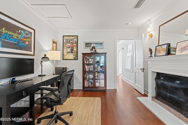 office with ornamental molding, wood finished floors, visible vents, and baseboards