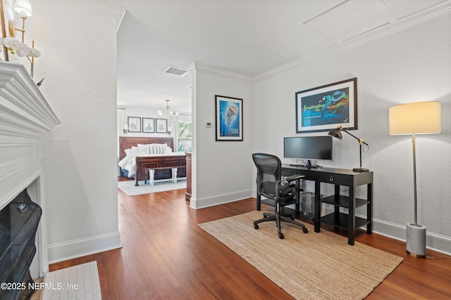 home office with visible vents, baseboards, wood finished floors, crown molding, and a notable chandelier