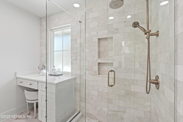 bathroom featuring a shower stall, baseboards, and vanity