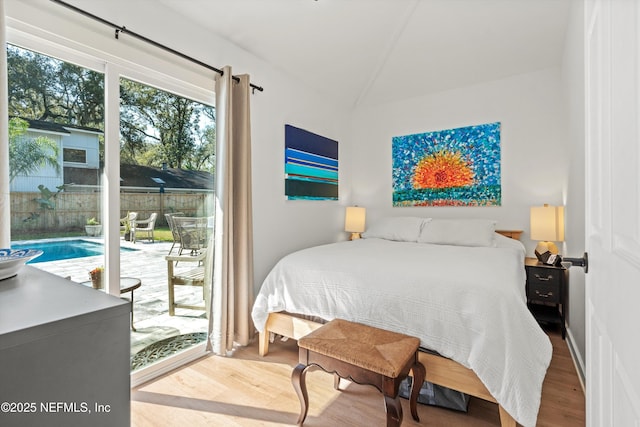 bedroom with lofted ceiling, access to outside, and wood finished floors