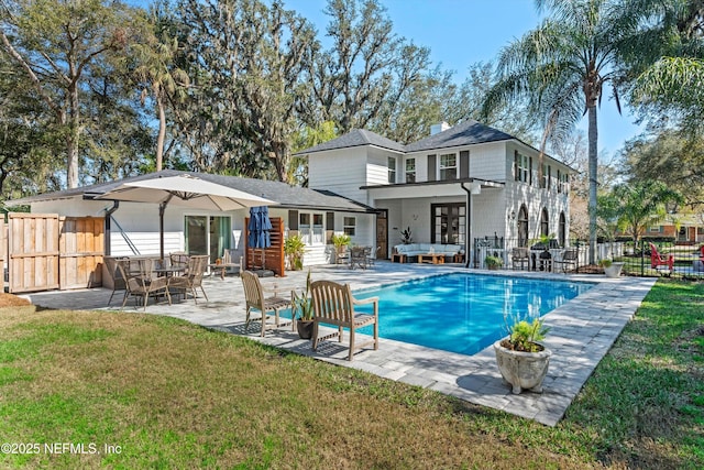 rear view of house with a fenced in pool, fence, a patio, and a yard