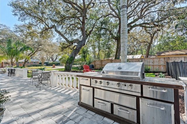 view of patio with grilling area, fence, and an outdoor kitchen