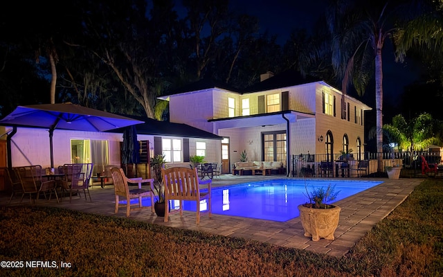 back of house at twilight featuring an outdoor pool, a patio, and an outdoor hangout area