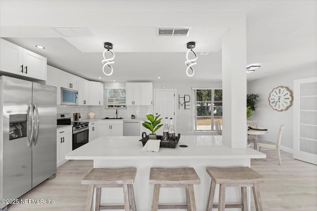 kitchen featuring appliances with stainless steel finishes, visible vents, a sink, and a kitchen bar