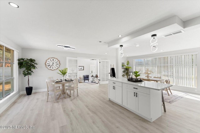 kitchen featuring light wood-style floors, a kitchen island, visible vents, and white cabinets