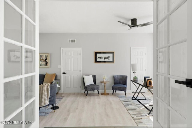 sitting room featuring french doors, visible vents, ceiling fan, and wood finished floors