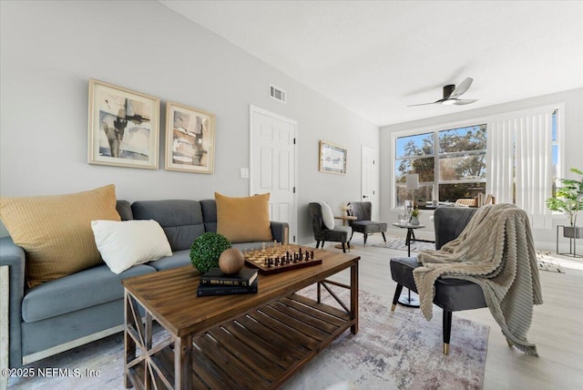 living area featuring light wood-style flooring, visible vents, and a ceiling fan