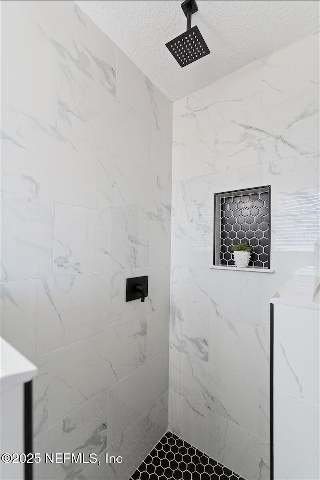 bathroom with a textured ceiling and tiled shower