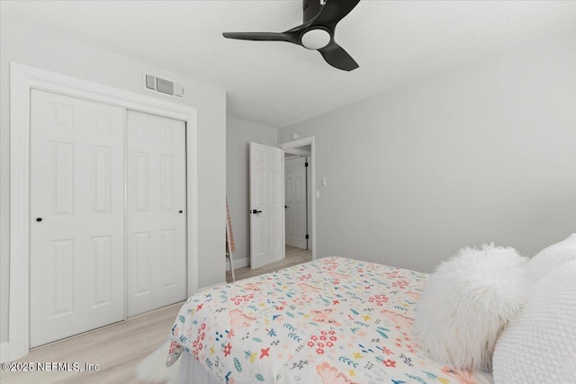 bedroom with light wood finished floors, a closet, visible vents, and a ceiling fan