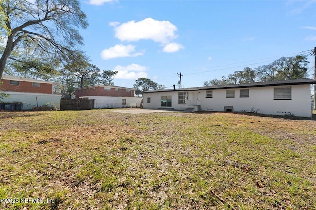 rear view of house featuring a patio, a yard, and fence