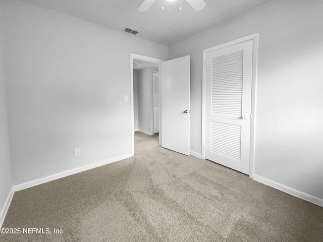 unfurnished bedroom featuring baseboards, visible vents, a ceiling fan, carpet floors, and a closet