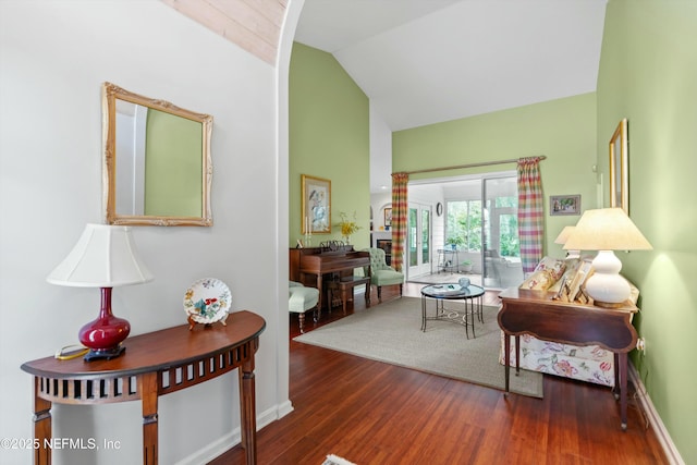 living room featuring vaulted ceiling, baseboards, and wood finished floors