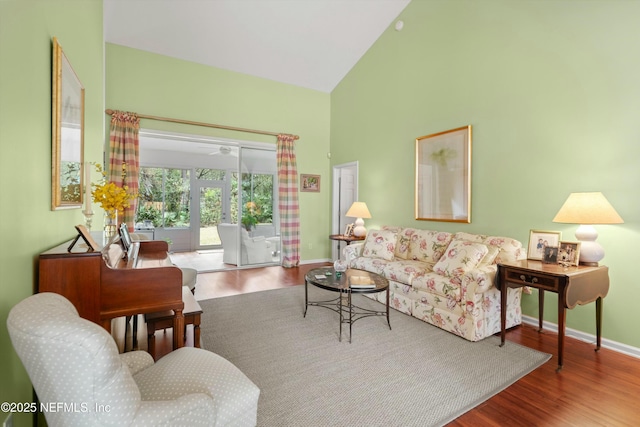 living area with baseboards, high vaulted ceiling, and wood finished floors