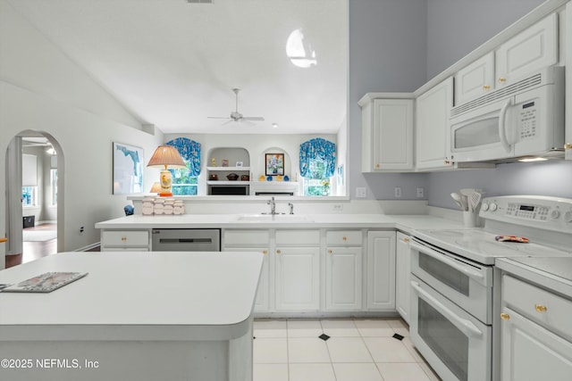 kitchen with arched walkways, light countertops, white cabinetry, a sink, and white appliances