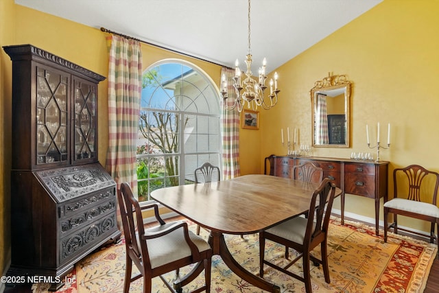 dining room with lofted ceiling, baseboards, a notable chandelier, and wood finished floors