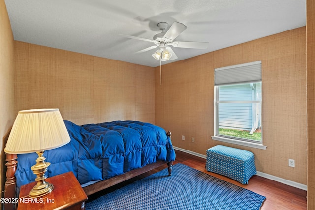 bedroom with baseboards, ceiling fan, wood finished floors, and wallpapered walls