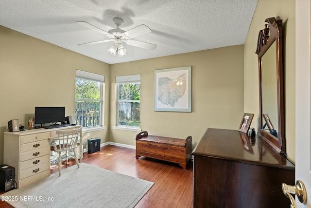 office space featuring a ceiling fan, a textured ceiling, baseboards, and wood finished floors