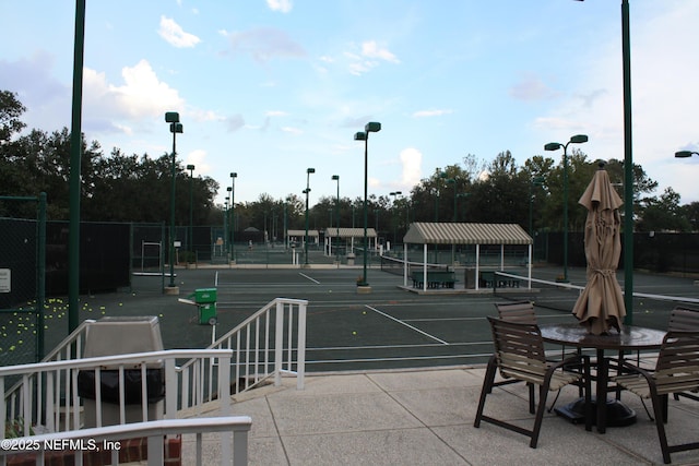 view of community with a tennis court and fence