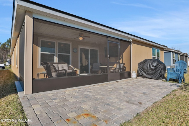 back of house featuring a sunroom, a patio area, a ceiling fan, and stucco siding