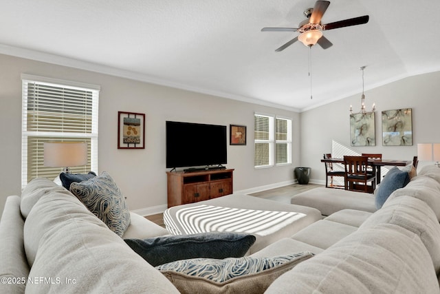 living room with ornamental molding, vaulted ceiling, wood finished floors, baseboards, and ceiling fan with notable chandelier