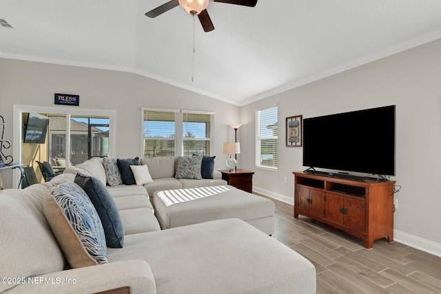 living area with wood finish floors, lofted ceiling, ornamental molding, ceiling fan, and baseboards