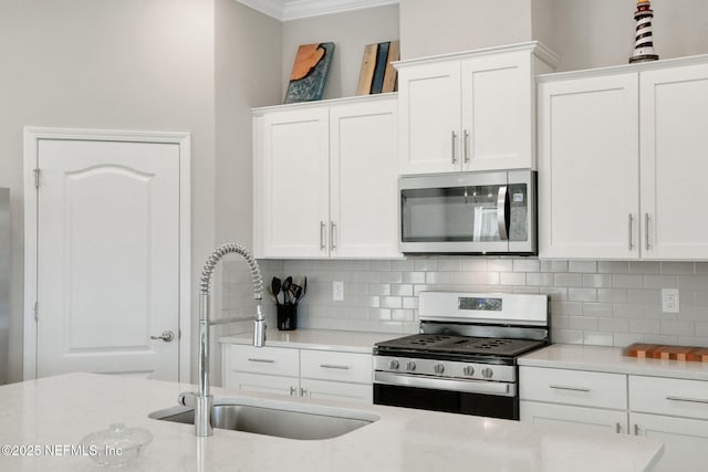 kitchen with backsplash, white cabinetry, stainless steel appliances, and a sink