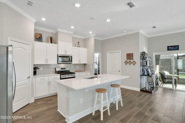 kitchen with tasteful backsplash, visible vents, stainless steel appliances, wood finish floors, and a sink