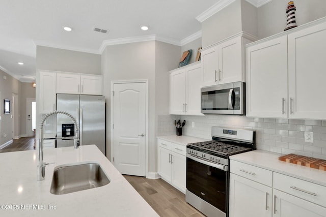 kitchen featuring stainless steel appliances, light wood-style flooring, a sink, and visible vents