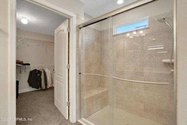 full bathroom with a textured ceiling, a spacious closet, and a stall shower