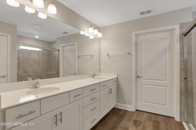 full bath featuring a stall shower, visible vents, a sink, and wood finish floors