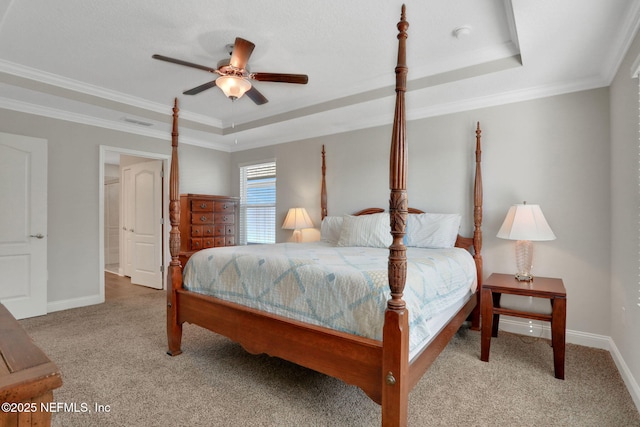 carpeted bedroom featuring ornamental molding, a tray ceiling, and baseboards