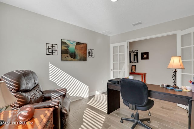 office space with visible vents, baseboards, a textured ceiling, and wood finish floors